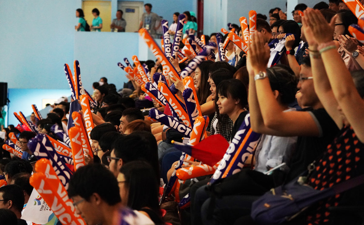 Badminton fans cheering with Victor clappers at a tournament
